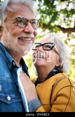 Couple caucasien adulte riant debout embrassé affectueusement dans la rue touristique de la ville. Banque D'Images