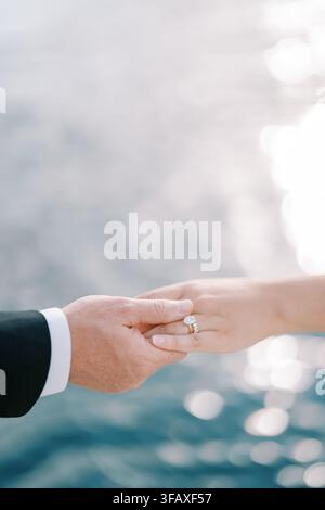 Gros plan d'un couple se tenant la main au bord de l'eau Banque D'Images