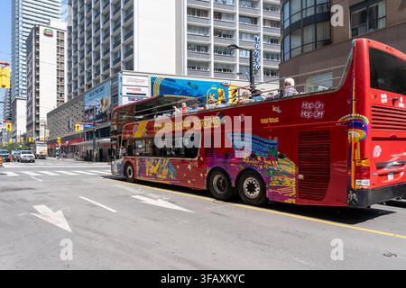 Un bus double-decker rouge à toit ouvert City Sightseeing Hop On Hop Off descendant une rue du centre-ville de Toronto. Banque D'Images