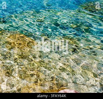 Eau de mer turquoise transparente ondulant sur un fond océanique rocheux peu profond, Tropea, Italie. Banque D'Images
