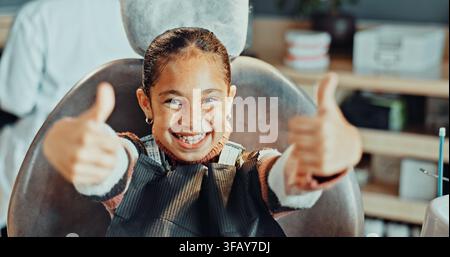 Portrait, fille ou dentiste avec les pouces levés dans la clinique pour l'hygiène dentaire, le traitement ou le succès. Enfant, gamin ou patient avec un grand sourire, comme un émoji ou oui Banque D'Images