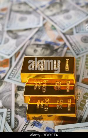 Concept d'investissement en or et de préservation de la richesse avec des lingots d'or purs empilés sur des billets de cent dollars pour la réserve financière et la couverture contre l'inflation. Banque D'Images