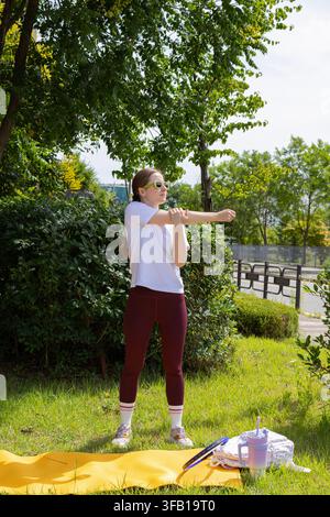 Femme sportive s'échauffant avec un étirement des bras avant un exercice en plein air Banque D'Images