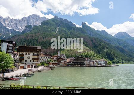 Le village d'Alleghe se reflétant dans un lac entouré des montagnes des Dolomites Banque D'Images