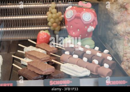 Sélection de douceurs colorées, fruits candisés et desserts au chocolat exposés sur un stand traditionnel de fête foraine. Banque D'Images