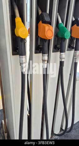 Range de becs de distributeur de carburant colorés à la station-service Banque D'Images