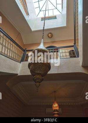 Intérieur traditionnel d'un riad marocain à Marrakech, avec un escalier élégant, des rampes en métal ornées, des lanternes décoratives, un mobilier traditionnel a Banque D'Images