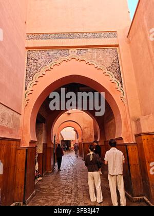 Passage traditionnelle marocaine dans la médina de Marrakech, présentant des arches en fer à cheval ornées, des calligraphies arabes et des panneaux muraux en bois. Banque D'Images