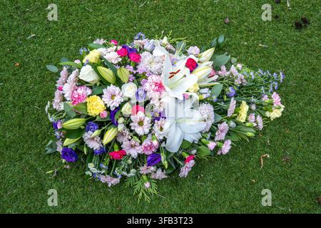 Une vue aérienne d'un arrangement coloré en forme de cercueil funéraire comprenant des lys blancs, des roses, des œillets et des chrysanthèmes, posé à l'extérieur Banque D'Images
