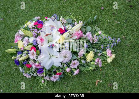 Une vue aérienne d'un arrangement coloré en forme de cercueil funéraire comprenant des lys blancs, des roses, des œillets et des chrysanthèmes, posé à l'extérieur Banque D'Images