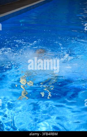 Homme qui se noie dans une piscine bleue profonde, gros plan, personne sous l'eau qui coule et lutte pour respirer, mettant en évidence une crise de survie d'urgence et eau Banque D'Images