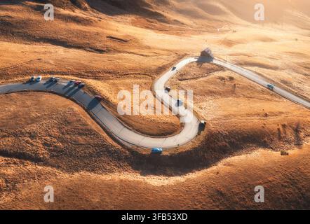 Route de montagne sinueuse avec des voitures sur une pente d'herbe jaune. Vue aérienne Banque D'Images