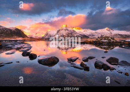Montagnes enneigées reflétées dans l'eau du fjord au coucher du soleil Banque D'Images