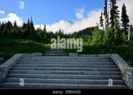 Des marches de pierre gravées d'une citation de John Muir menant à un sentier montagneux pittoresque avec le mont Rainier s'élevant au-dessus des nuages, État de Washington, États-Unis. Banque D'Images