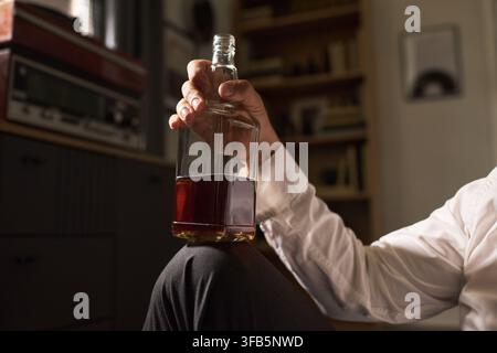 Homme déprimé tenant une bouteille d'alcool souffrant d'addiction Banque D'Images