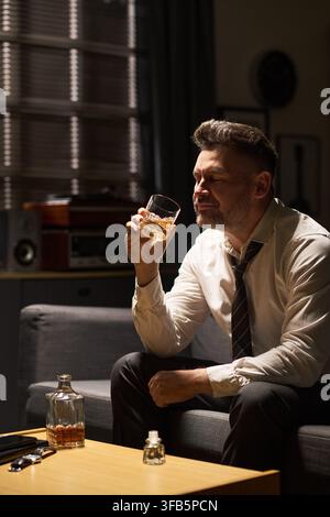Homme d'âge moyen déprimé buvant du whisky seul à la maison Banque D'Images