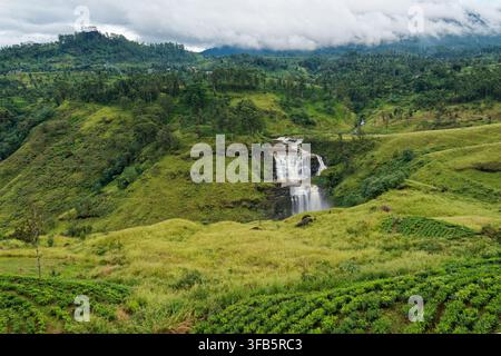 Vue aérienne d'une cascade à plusieurs niveaux dévalant à travers les hautes terres brumeuses du Sri Lanka, les plantations de thé luxuriantes et les collines ondulantes, un paysage tropical pittoresque Banque D'Images