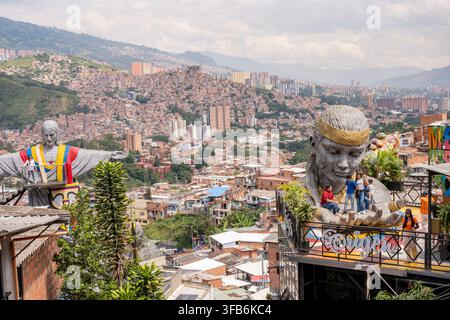 Medellin, Colombie – 15 janvier 2026 : paysage urbain de la commune 13 mettant en vedette de grandes sculptures fréquentées par des visiteurs, avec vue sur le quartier densément peuplé des collines Banque D'Images