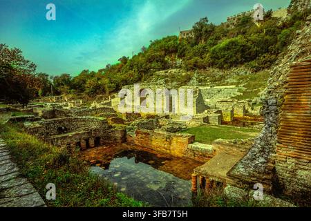 Ruines grecques anciennes avec l'Étang des Tortues, site archéologique sous un ciel nuageux dramatique, forêt en pente. Butrint, Comté de Vlorë, Albanie, Europe Banque D'Images