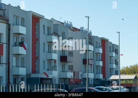 Immeubles d'appartements modernes décorés de drapeaux nationaux polonais sur les balcons par une journée ensoleillée. Concept de patriotisme, célébration nationale, résidence Banque D'Images