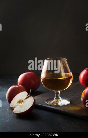 Verre au brandy Calvados et pommes rouges sur noir. Banque D'Images