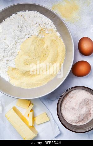 Ingrédients pour des pâtes. Farine et semoule de blé dur dans un bol. Œufs, beurre et sel sur la table. Vue de dessus d'un plan de travail de cuisine. Banque D'Images
