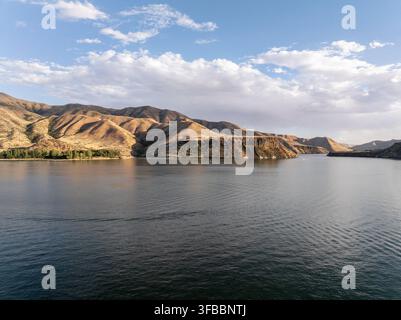 Vue aérienne d'un lac tranquille entouré de collines ondulantes sous un ciel partiellement nuageux Banque D'Images