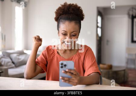 Femme heureuse célébrant de bonnes nouvelles reçues par SMS Banque D'Images