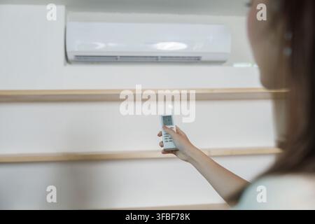 Main coupée tenant une télécommande pour régler la température du climatiseur à la maison Banque D'Images
