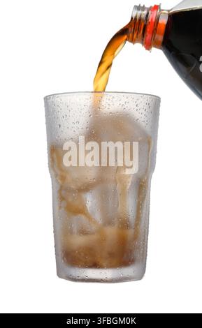 Photo d'action puissante montrant un liquide Coca-Cola sortant d'une bouteille dans un verre rempli de glace, capturé à mi-versement sur fond blanc propre. Phot énergie de marque Banque D'Images