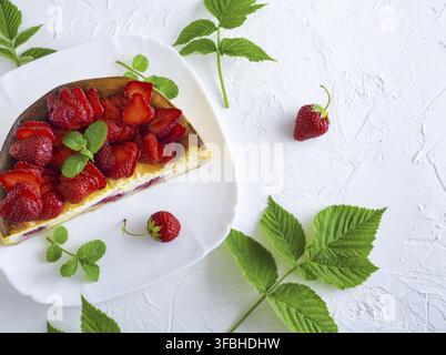 La moitié du gâteau au fromage avec des fraises fraîches sur une plaque carrée blanc, blanc table, espace vide, vue du dessus Banque D'Images