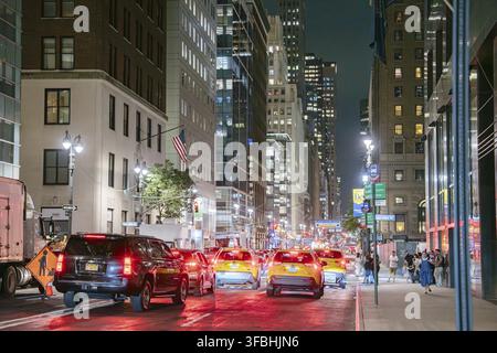 New York City, New York, États-Unis - 07.30.2024 : Des taxis jaunes et des voitures s'alignent sur East 44th Street dans le Midtown Manhattan la nuit. La rue est brillamment éclairée avec Banque D'Images
