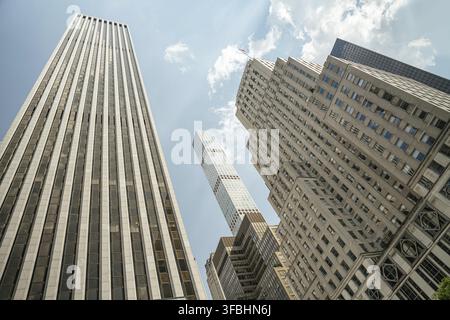 Les gratte-ciel imposants s'élèvent au-dessus des rues de Midtown Manhattan sous un ciel d'été radieux. Les bâtiments modernes en verre contrastent avec l'architecture historique Banque D'Images