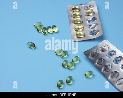 huile de poisson en capsules et blister sur fond bleu, supplément alimentaire pour la santé, gros plan Banque D'Images