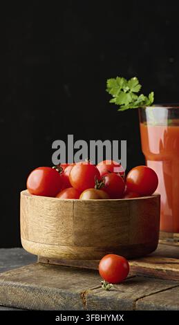 Tomates cerises rouges dans un bol en bois. Fond noir Banque D'Images