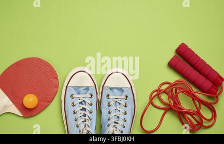 baskets, corde à sauter et raquettes en bois pour le tennis de table sur fond vert, place pour une inscription, plat Banque D'Images