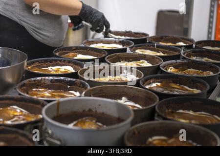 chef pâtissier préparant et cuisant une croûte de chocolat de groupe pour le cheesecake au caramel salé dans une cuisine professionnelle Banque D'Images