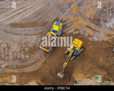 Vue aérienne d'une pelleteuse et d'un camion-benne travaillant dans la mine à ciel ouvert de lignite de Hambach, avec les traces des machines lourdes visibles sur la terre brune Banque D'Images