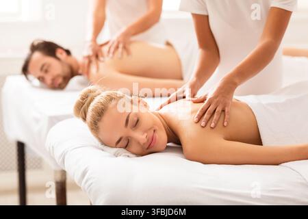 Les conjoints détendus bénéficient d'un massage sur les lits au centre de spa Banque D'Images