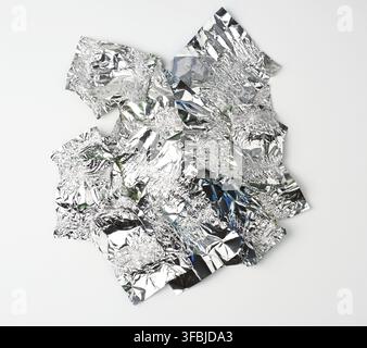 diverses feuilles d'aluminium froissés utilisaient des enveloppeurs de bonbons sur un fond blanc, vue de dessus Banque D'Images