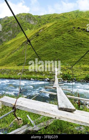 Pont suspendu instable sur sentier de randonnée. Pont suspendu en bois sur rivière de montagne Banque D'Images