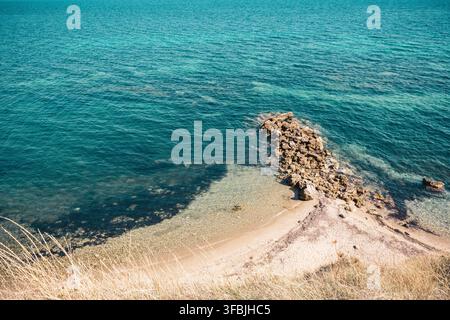 Vue en hauteur de l'eau turquoise claire de la mer et d'une côte rocheuse avec une plage de sable vue du dessus, Nea Fokea, Grèce. Banque D'Images