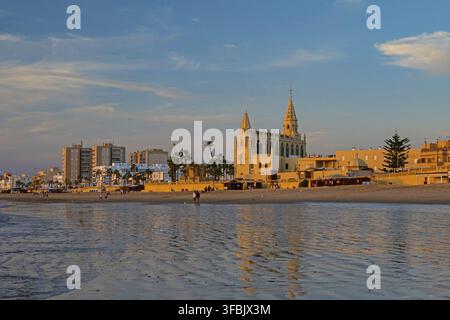 La plage de La Regla à Chipiona avec église et phare dans une lumière chaude du soir Banque D'Images