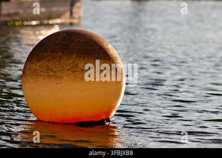 Une bouée ronde érodée flotte sur l'eau ondulante à Long Beach. Banque D'Images