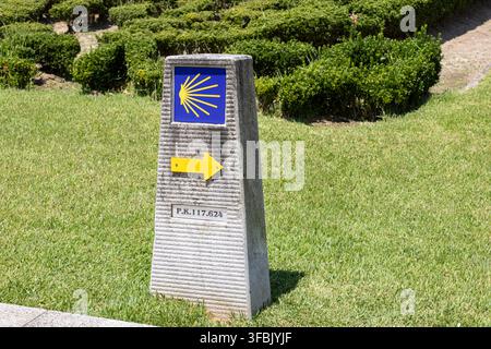 Chemin de Compostelle voie portugaise marqueur de milestone en pierre avec coquille et flèche jaune Banque D'Images
