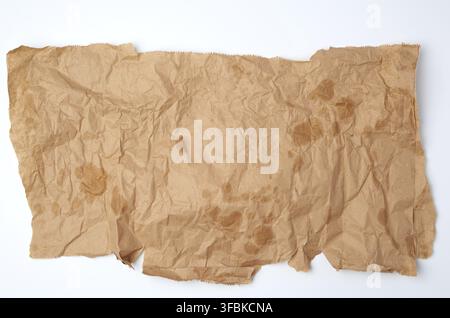 Morceau de tissu déchiré papier brun avec des taches de graisse sur un fond blanc, vue du dessus Banque D'Images