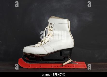 patins en cuir blanc pour le patinage artistique, stand sur fond de bois marron, équipement sportif Banque D'Images
