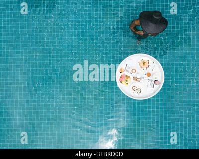 Femme profitant d'un petit-déjeuner flottant dans une piscine Banque D'Images