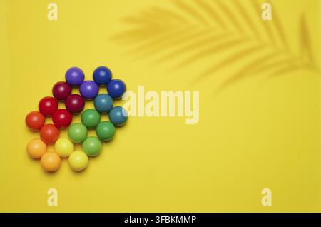 Fond abstrait avec des boules en plastique multicolores sur un fond jaune, une scène pour la démonstration de cosmétiques et de produits Banque D'Images