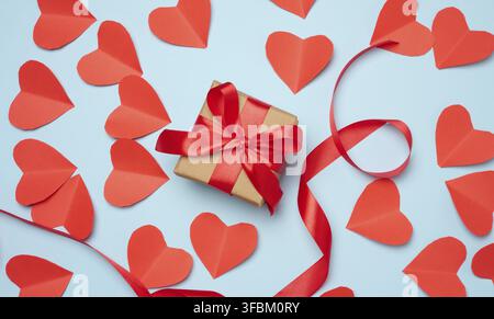Boîte cadeau avec ruban de satin rouge et noeud sur un fond bleu.fond de vacances Banque D'Images